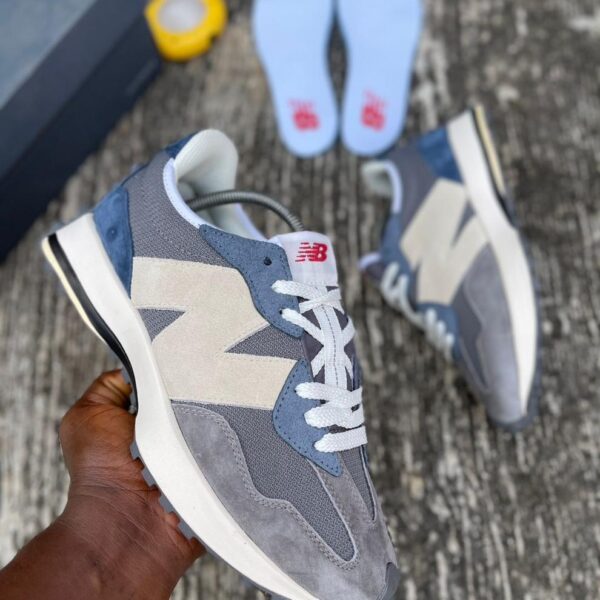 A pair of grey, white, and blue New Balance 574 sneakers, perfect for men's casual wear, with a comfortable fit and stylish design.