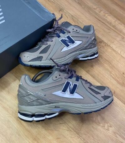 A pair of grey and blue New Balance 990R shoes with box on a wooden floor, perfect for men seeking comfort and style.