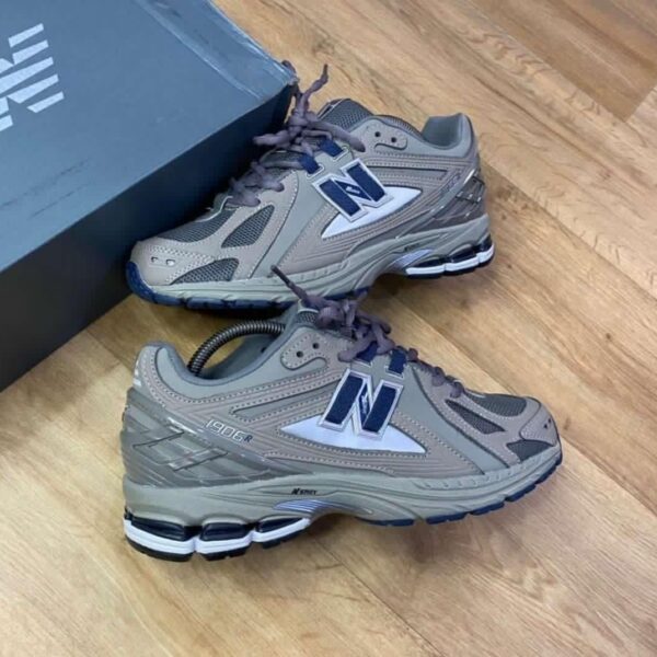 A pair of grey and blue New Balance 990R shoes with box on a wooden floor, perfect for men seeking comfort and style.