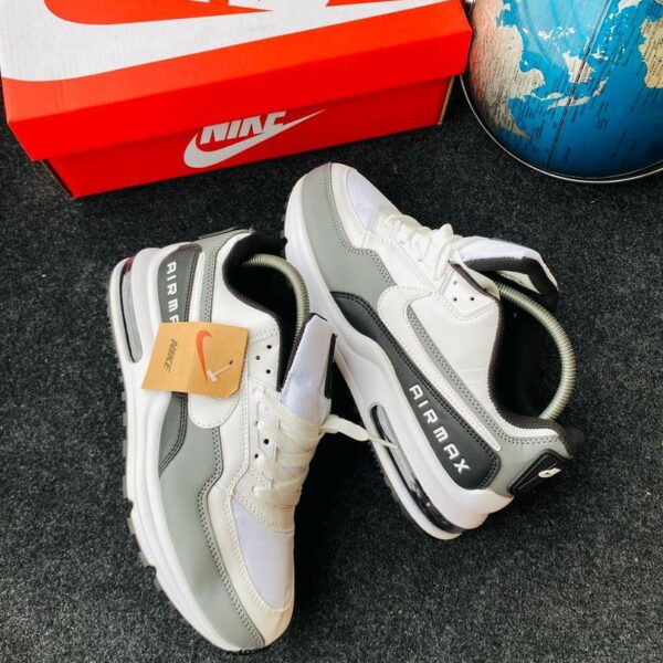 A pair of white and grey Nike Air Max sneakers with a red Nike shoe box and a blue globe in the background, showcasing the shoe's stylish design and comfort features.