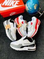 A pair of white and grey Nike Air Max sneakers with a red Nike shoe box and a blue globe in the background, showcasing the shoe's stylish design and comfort features.