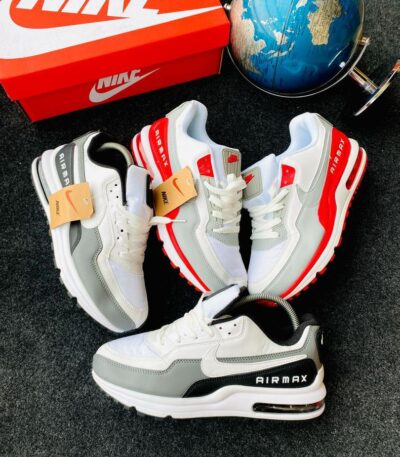 A pair of white and grey Nike Air Max sneakers with a red Nike shoe box and a blue globe in the background, showcasing the shoe's stylish design and comfort features.