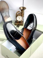A pair of dark brown leather loafers from Richwanaz, displayed in an open box with a clock and other accessories.