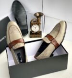 A pair of black leather loafers with perforated details in a shoe box, exuding luxury and sophistication.