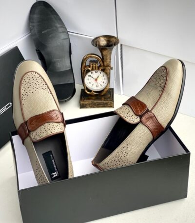 A pair of black leather loafers with perforated details in a shoe box, exuding luxury and sophistication.