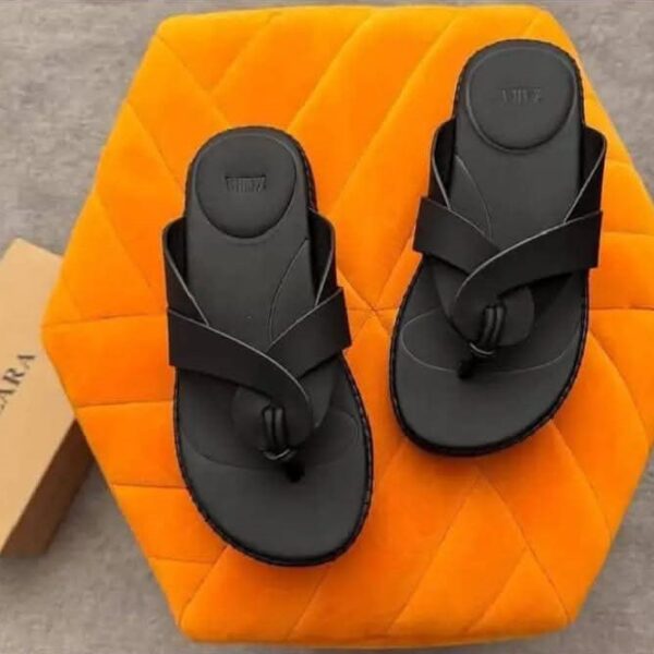 A pair of black double strap sandals on an orange hexagonal pillow with a shoe box, showcasing ArvoLuxury's premium design and comfort.