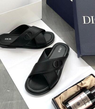 A pair of luxurious black leather Dior sandals on a white background, showcasing the sleek design and branding, ideal for comfort and class.