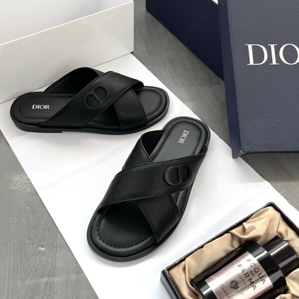 A pair of luxurious black leather Dior sandals on a white background, showcasing the sleek design and branding, ideal for comfort and class.