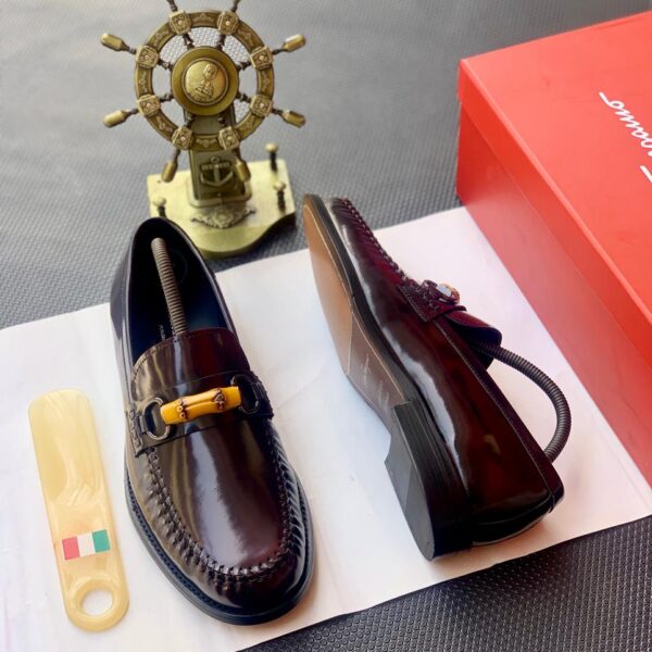 A pair of dark brown leather loafers with tassel detailing, presented on a white paper with a shoe horn and red shoe box in the background, showcasing ArvoLuxury's commitment to premium footwear.
