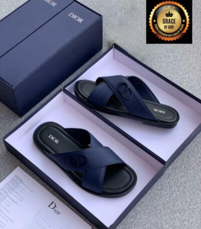 A pair of navy blue Dior slide sandals in an open box with documentation and a navy blue lid, showcasing luxury and elegance.