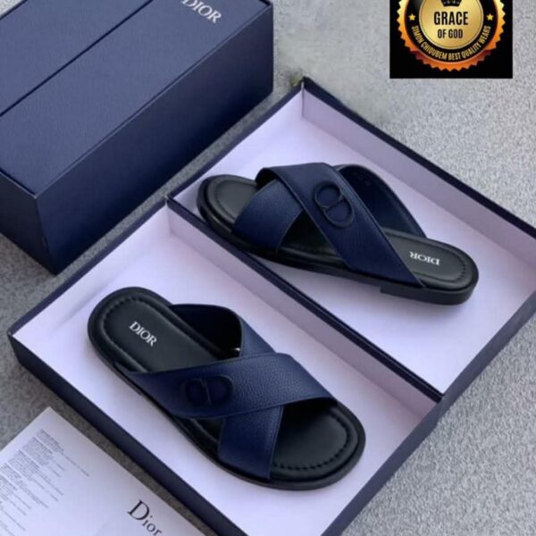 A pair of navy blue Dior slide sandals in an open box with documentation and a navy blue lid, showcasing luxury and elegance.