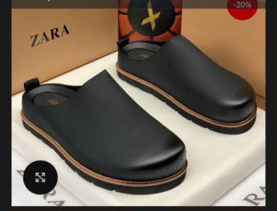 A pair of black leather clog shoes with tan accents, presented on a white box with a Zara box in the background, showcasing ArvoLuxury's commitment to premium footwear.