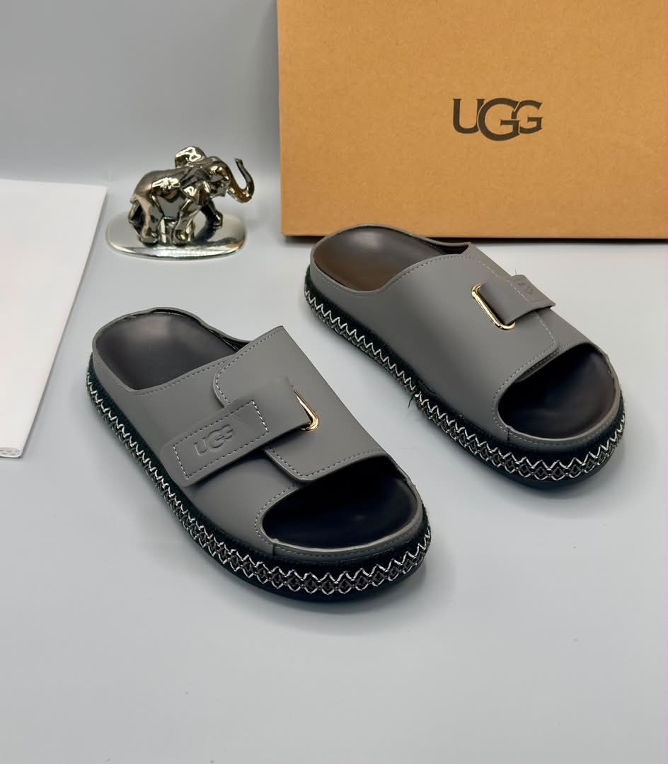 root Grey UGG slide sandals with gold accents and stitched sole, presented with a UGG box and luxury accessories.