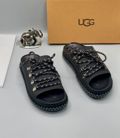 A pair of black leather open-toe sandals with metal buckles and laces, exuding luxury and sophistication.