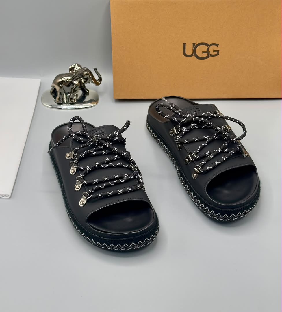 root A pair of black leather open-toe sandals with metal buckles and laces, exuding luxury and sophistication.