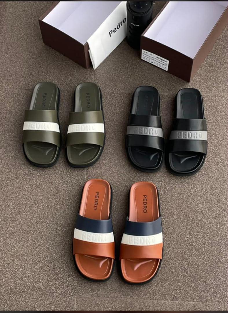 root A display of three pairs of Pedro two-strap slide sandals in olive green, black, and terracotta, with their respective shoe boxes.