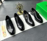 A pair of black leather oxfords with brogue detailing, accompanied by a shoe tree and presented on a crisp white background.