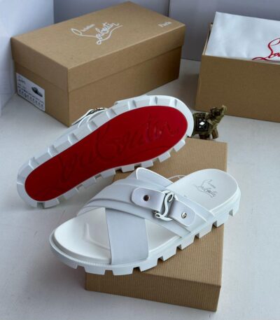 A pair of pristine white slides with a striking red sole, nestled on a brown shoe box, exuding high-end sophistication.