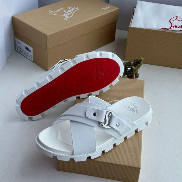 A pair of pristine white slides with a striking red sole, nestled on a brown shoe box, exuding high-end sophistication.