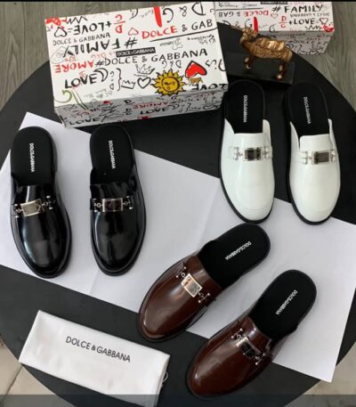A stylish display of Dolce & Gabbana loafers in black, brown, and white, accompanied by the brand's signature box and cloth bag.