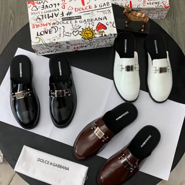 A stylish display of Dolce & Gabbana loafers in black, brown, and white, accompanied by the brand's signature box and cloth bag.