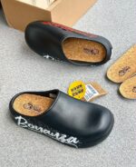 A pair of stylish black and grey shoes with distinctive designs, placed on a grey surface next to a shoe box.