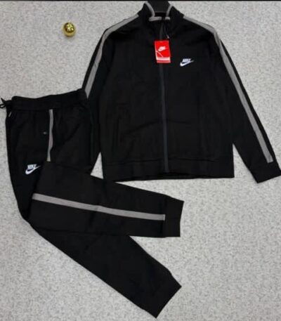 A stylish black tracksuit with grey accents and Nike logo, laid out on a grey surface.