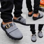 A stylish pair of grey loafers with a gold buckle and black sole, perfect for making a lasting impression.