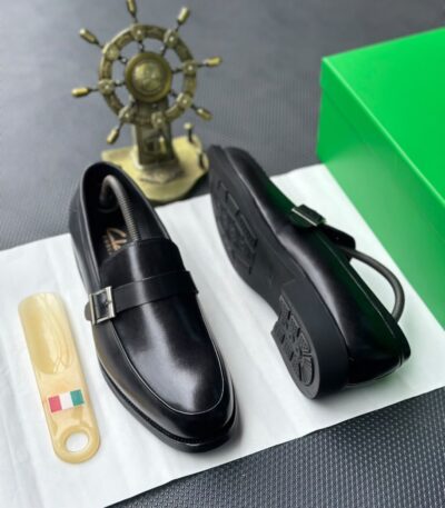 A pair of luxurious black leather loafers showcased on a pristine white surface, exuding elegance and refinement.