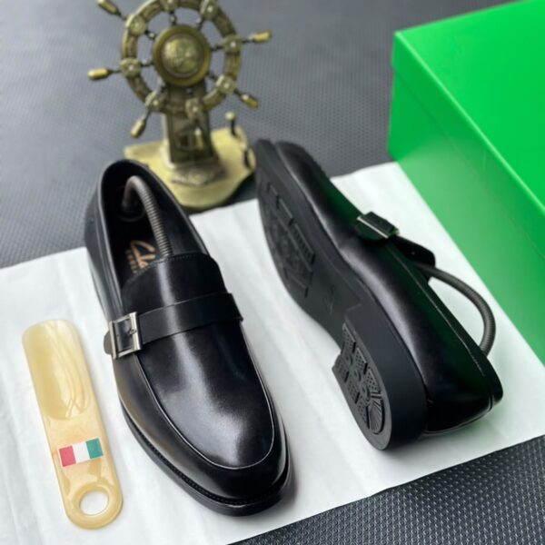 A pair of luxurious black leather loafers showcased on a pristine white surface, exuding elegance and refinement.