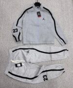 A stylish black tracksuit with grey accents and Nike logo, laid out on a grey surface.