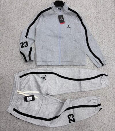 A stylish black tracksuit with grey accents and Nike logo, laid out on a grey surface.