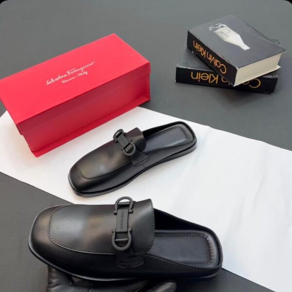 A pair of luxurious black leather loafers displayed with a red shoe box and two fashion books, embodying high-end style and comfort.