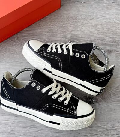 A pair of black sneakers with white laces and rubber soles, exuding luxury and comfort.